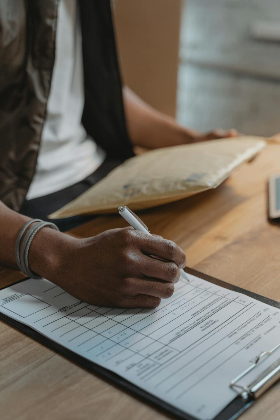 Person writing on a form on a clipboard.