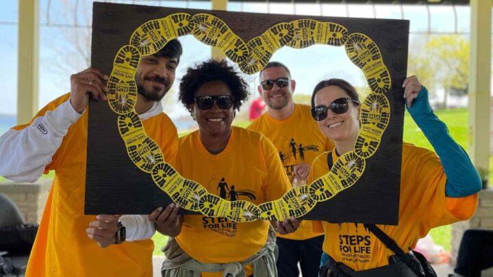 A group of four walkers stand within a heart-shaped Steps for Life frame.