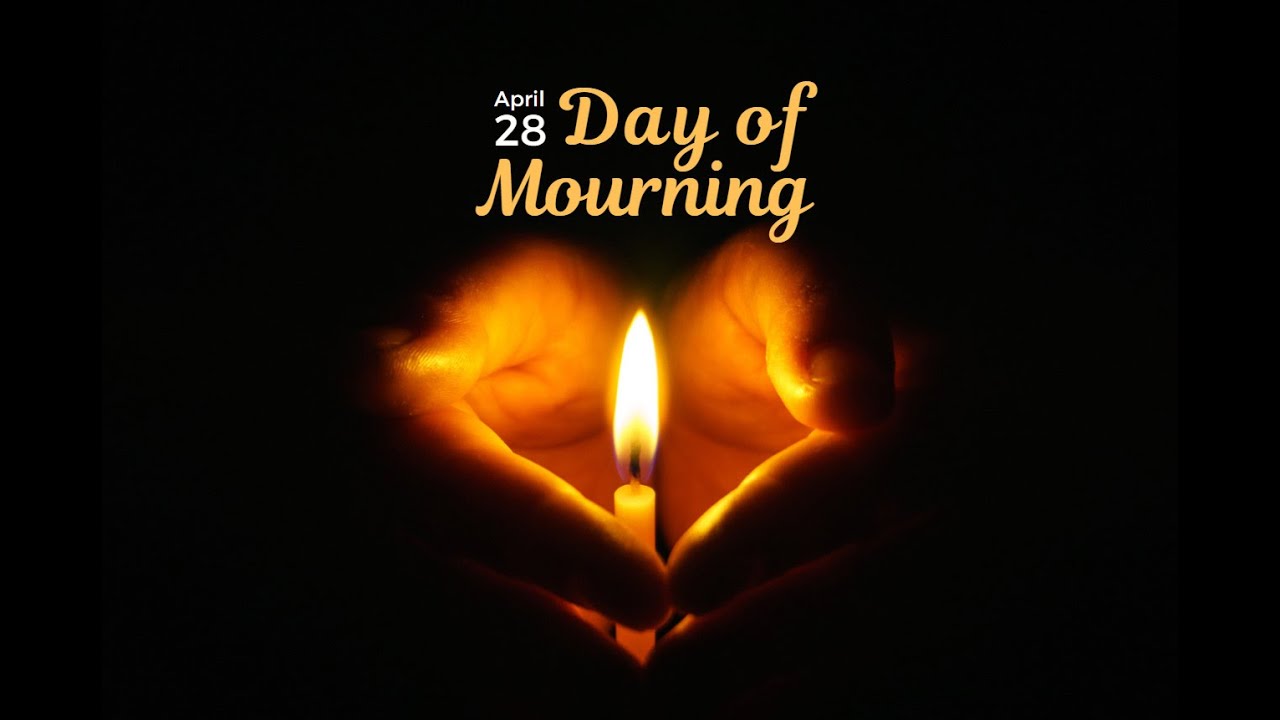 Two hands cup a single flame in darkness. The text reads "April 28 - Day of Mourning"