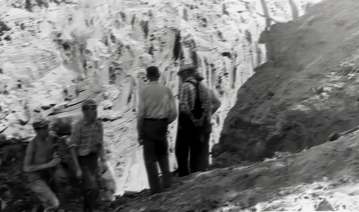 Old B&W photo showing men working in a deep pit.