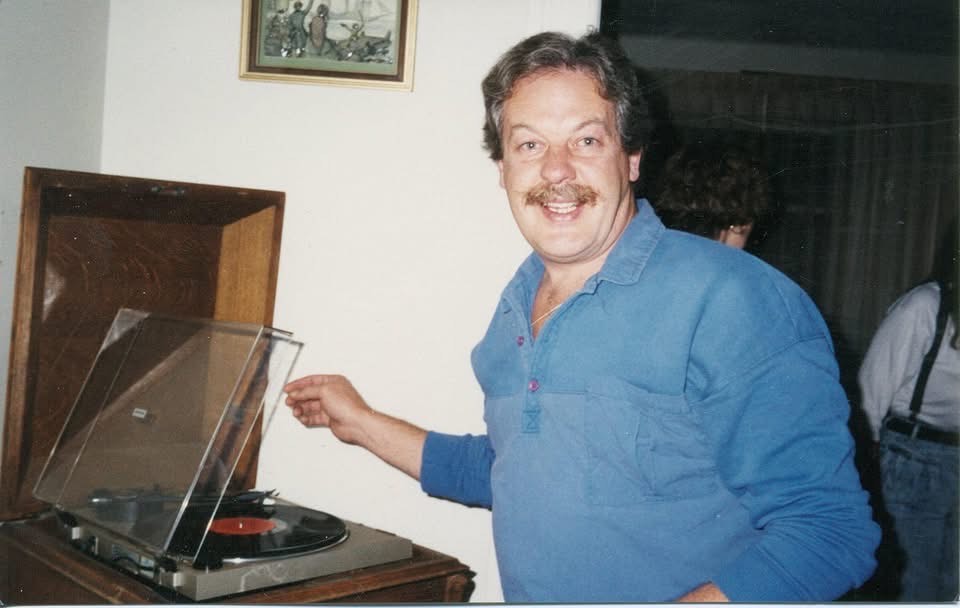 A man smiles as he opens a record player