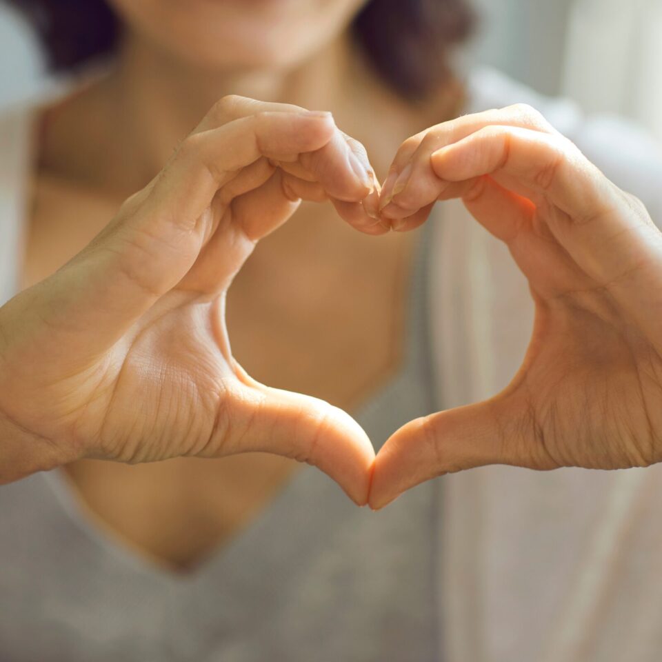 A person forms the shape of a heart with their two hands.